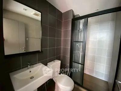 Modern bathroom with sleek design, featuring a glass shower enclosure and stylish fixtures.