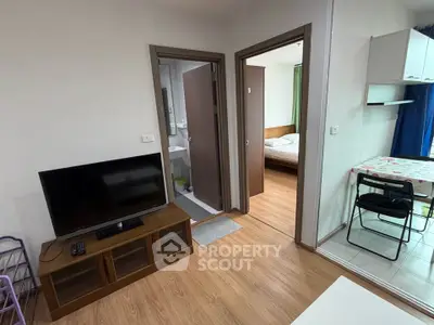 Cozy apartment interior with TV, bedroom, and dining area, featuring modern wooden flooring.