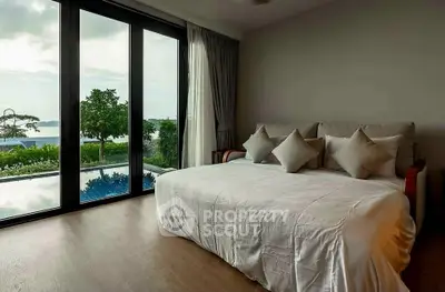Luxurious bedroom with stunning ocean view and large windows opening to a serene garden.