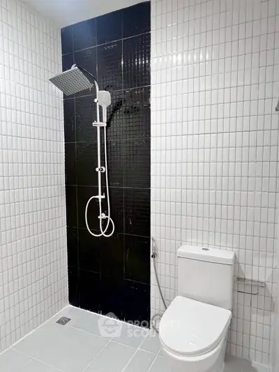 Modern bathroom with sleek black and white tile design and contemporary shower setup.