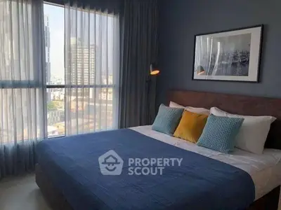 Stylish bedroom with city view, featuring modern decor and cozy bedding.