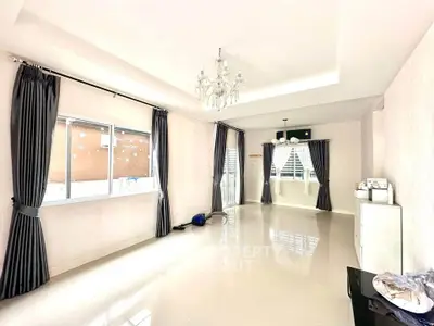 Spacious and bright living room with elegant chandelier and large windows.