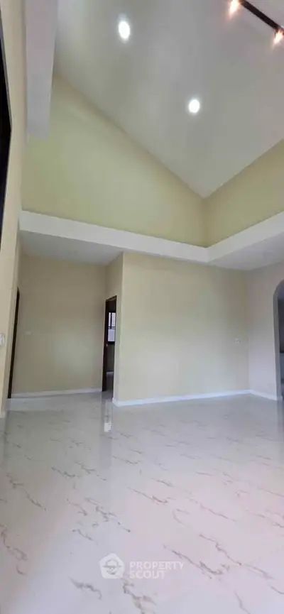 Spacious living room with high ceilings and elegant marble flooring.