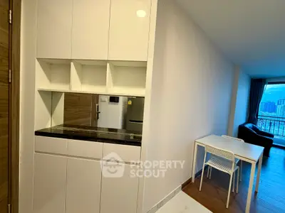 Modern apartment interior with sleek kitchen and dining area, featuring stylish cabinetry and city view.