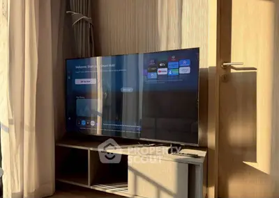 Modern living room with smart TV and sunlight streaming through curtains.