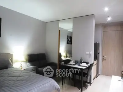 Modern studio apartment with cozy bed, sleek dining area, and stylish decor