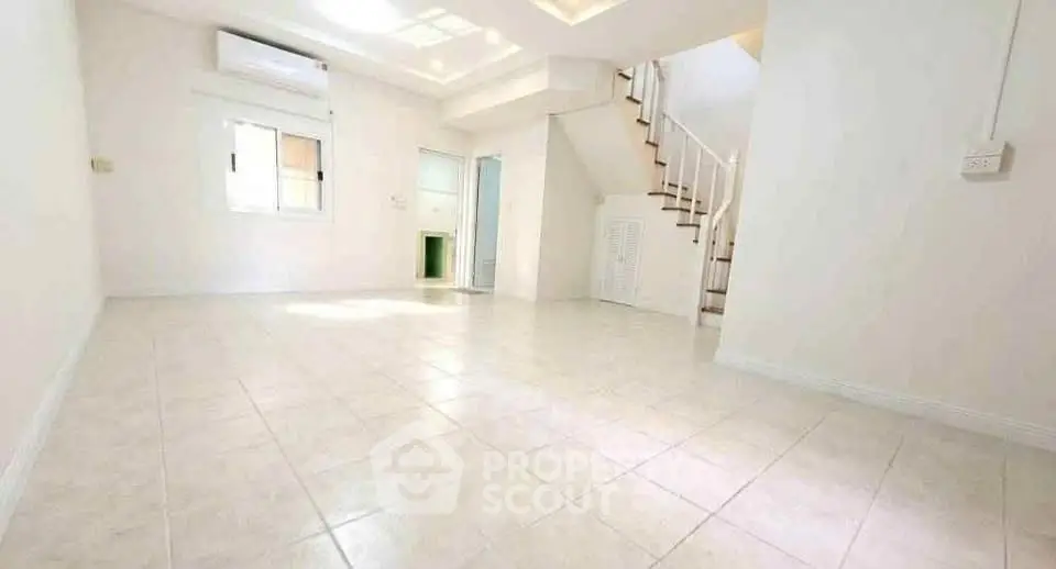 Spacious bright living room with staircase and tiled flooring in modern home