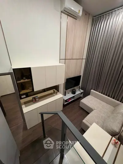 Modern living room with stylish furniture and high ceilings, featuring a cozy sofa and sleek entertainment unit.