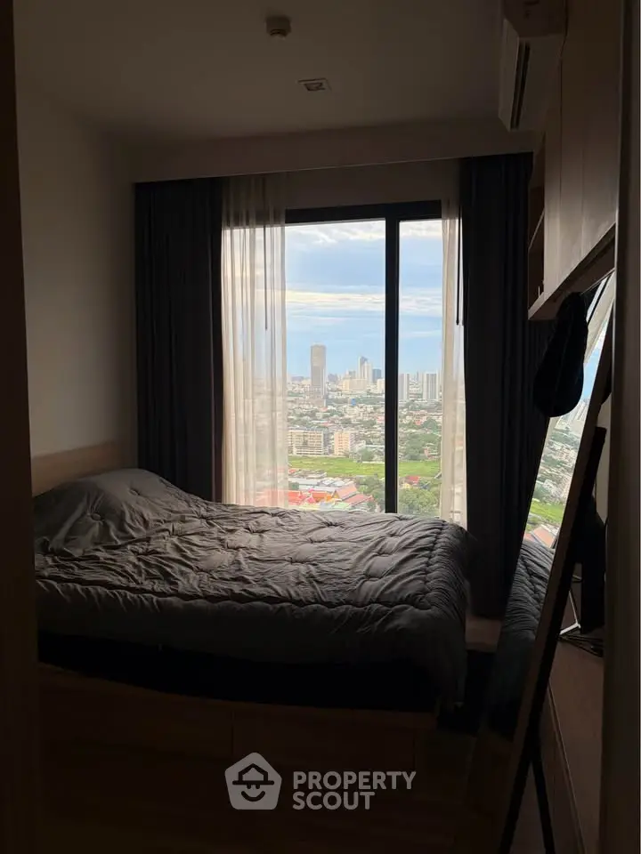 Cozy bedroom with stunning city view through large window, perfect for urban living.