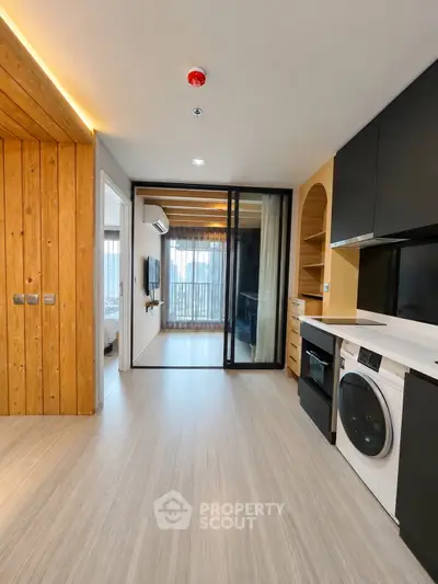 Modern apartment interior with sleek kitchen and laundry appliances, featuring wooden accents and glass sliding doors.