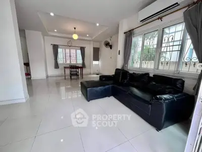 Spacious living room with modern black leather sofa and large windows