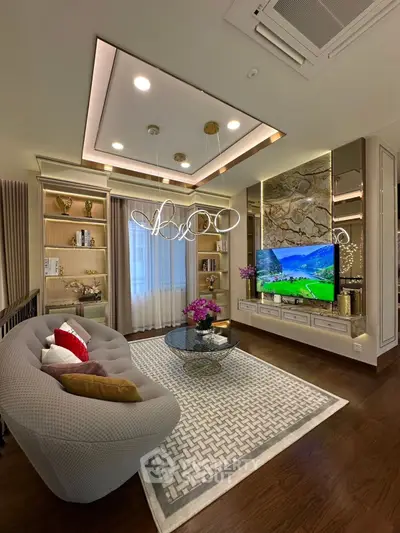 Luxurious living room with modern decor, elegant lighting, and a large TV, perfect for relaxation.