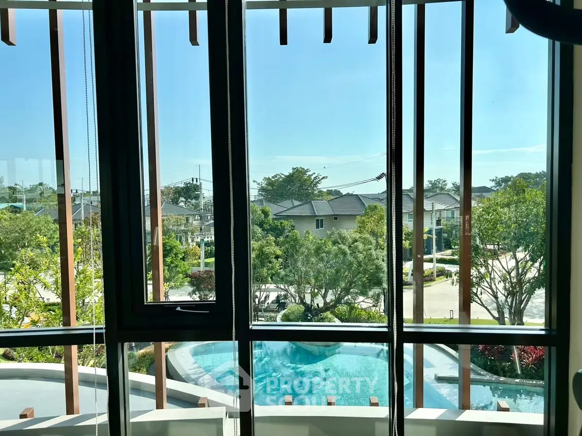 Stunning view from window overlooking pool and lush greenery in serene neighborhood.