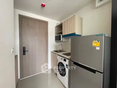 Compact modern kitchen with washing machine and fridge in a stylish apartment.