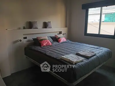 Cozy bedroom with modern decor and large window offering natural light.