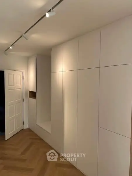 Modern minimalist hallway with sleek built-in storage and elegant lighting.