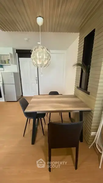 Modern dining area with stylish pendant light and wooden table in open layout kitchen.