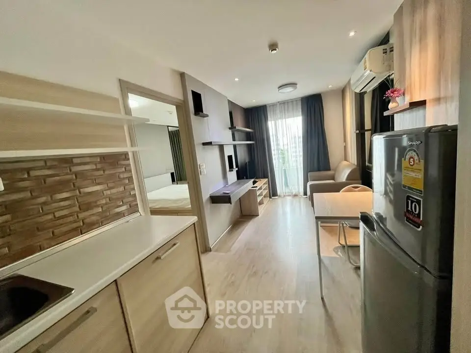 Modern open-layout apartment with kitchen and living area, featuring sleek design and natural light.