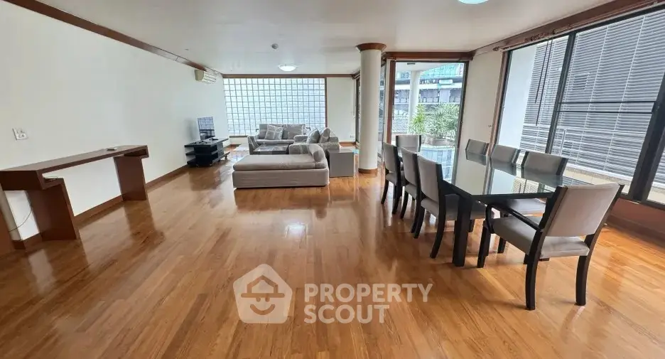 Spacious living room with hardwood floors and modern furniture in a bright apartment.