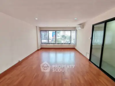 Spacious empty living room with large windows and wooden flooring