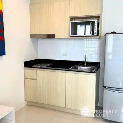 Modern compact kitchen with microwave and fridge in sleek apartment