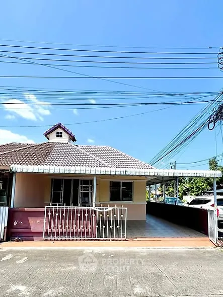 Charming single-story house with tiled roof and spacious driveway under clear blue sky.
