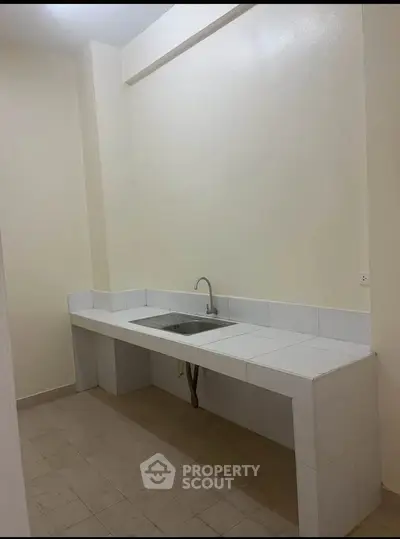 Minimalist kitchen with tiled countertop and sink in a compact space.