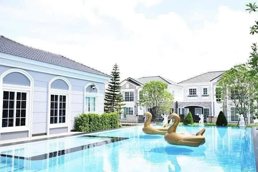 Luxurious residential complex with elegant pool and swan floats, surrounded by modern villas.
