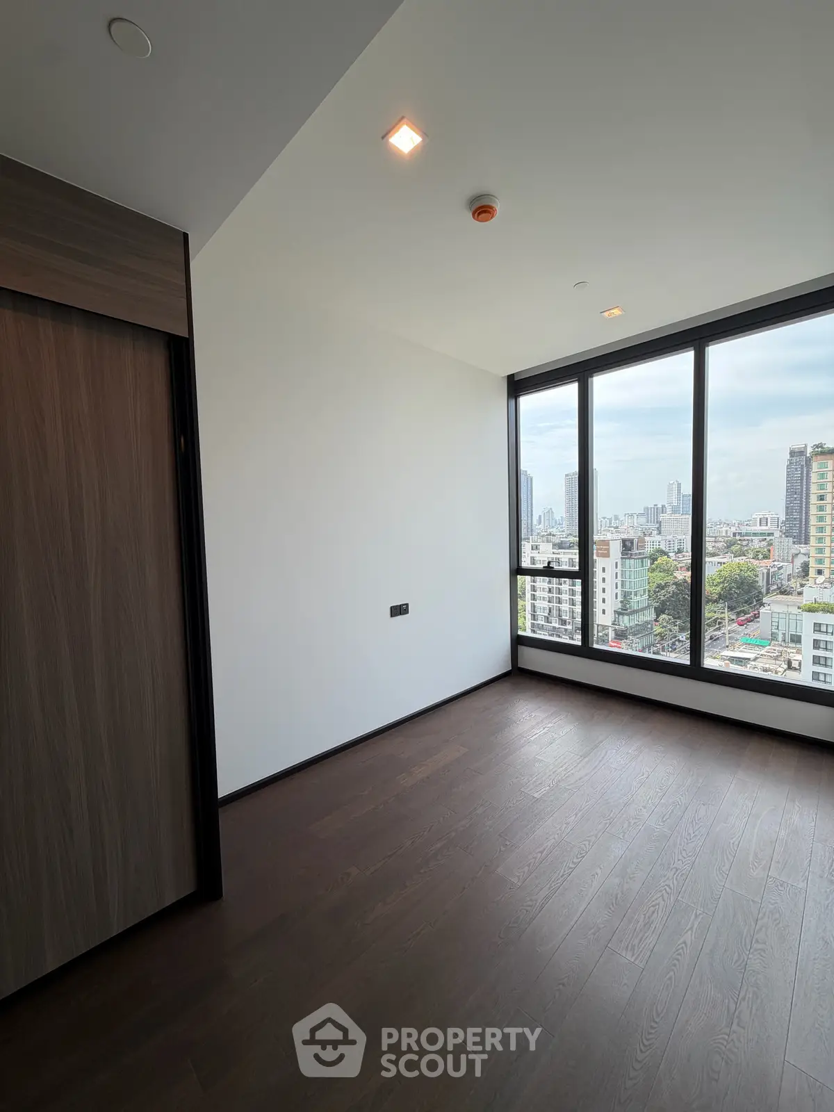 Spacious modern bedroom with large windows offering stunning city views.