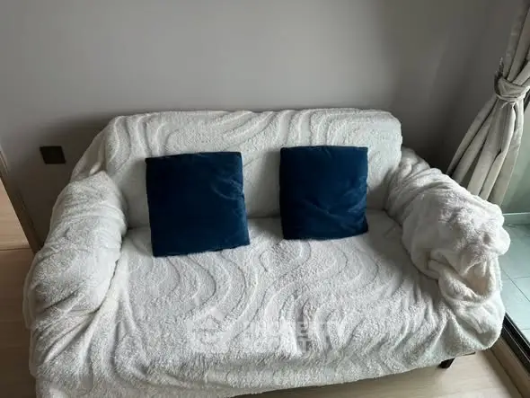 Cozy living room with plush white sofa and blue cushions, perfect for relaxation.