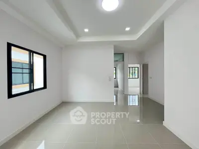 Spacious modern living room with sleek tile flooring and ample natural light.