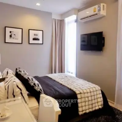 Modern bedroom with stylish decor and wall-mounted TV, featuring cozy bedding and framed art.