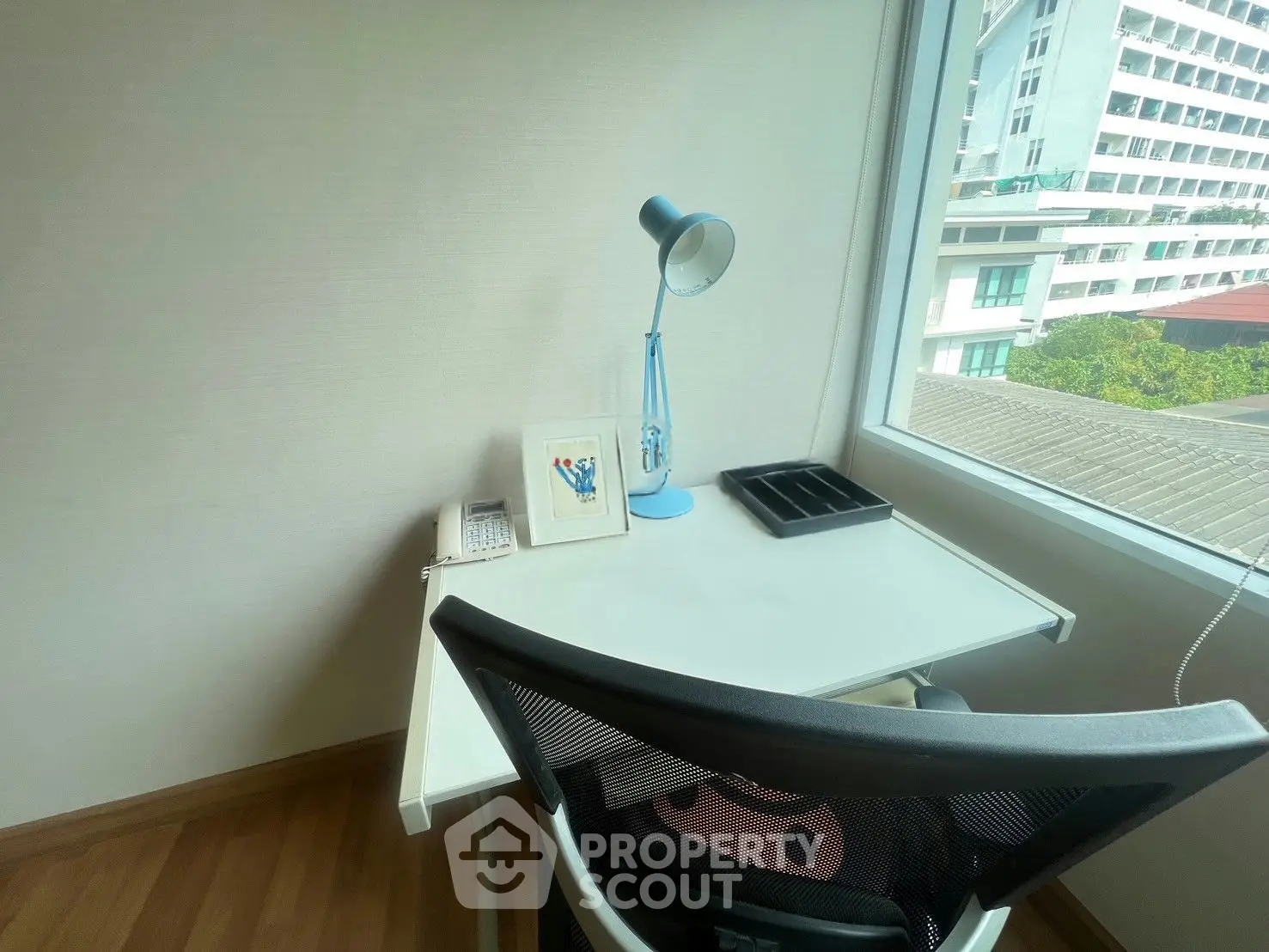 Bright study nook with desk, chair, and window view in modern apartment.