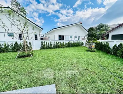 Charming suburban home with lush green lawn and white picket fence under a clear blue sky.