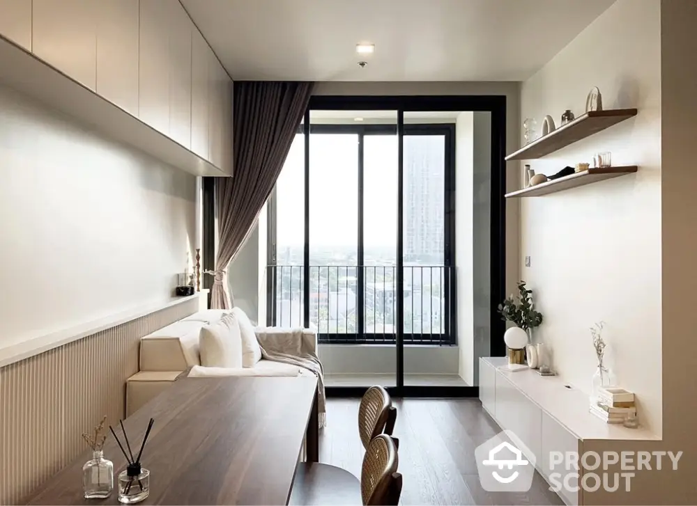 Modern living room with large window and balcony view, featuring stylish furniture and decor.