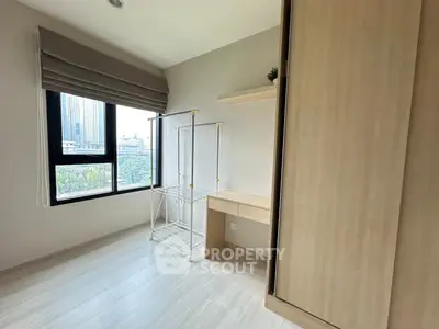 Bright bedroom with large window and modern wardrobe in a high-rise apartment.