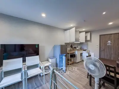 Modern open-layout living room with kitchen, featuring sleek furniture and appliances.