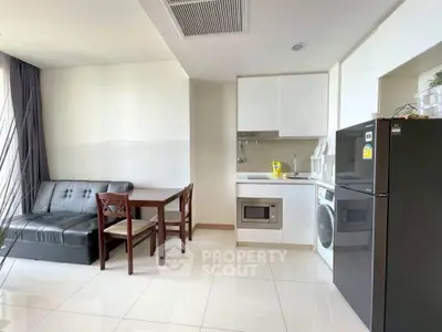 Modern apartment with sleek kitchen and cozy living area, featuring a washing machine and fridge.