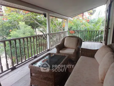 Charming balcony with cozy wicker furniture and lush garden view, perfect for relaxation.