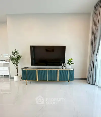 Modern living room with sleek TV stand and large flat-screen TV, elegant decor and natural light.