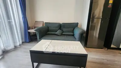 Modern living room with cozy sofa and sleek refrigerator, perfect for urban living.