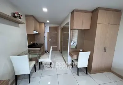 Modern compact kitchen and dining area with sleek wooden cabinetry and white chairs.