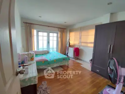 Spacious bedroom with wooden flooring and large windows for natural light.