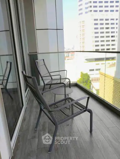 Modern balcony with city view and stylish outdoor seating in urban high-rise apartment.