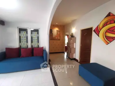 Spacious living room with modern decor and vibrant blue sofa, featuring elegant archway and artistic wall accents.