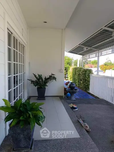 Charming home entrance with potted plants and spacious porch area, perfect for relaxation.