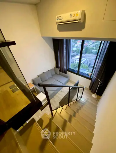 Modern loft with staircase and cozy living area featuring large window view.