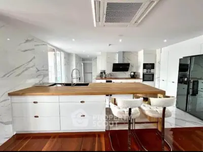 Luxurious modern kitchen with marble walls and wooden countertops, featuring high-end appliances and sleek design.