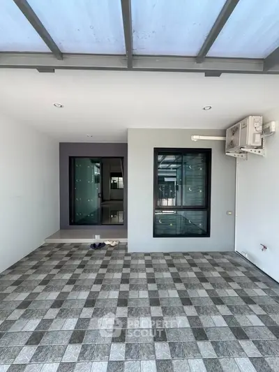 Modern tiled patio with large windows and air conditioning unit, perfect for outdoor relaxation.