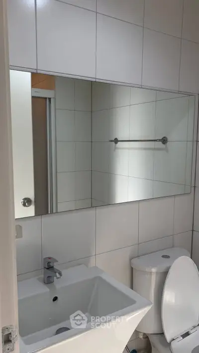 Modern bathroom with sleek white tiles and contemporary fixtures.